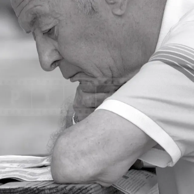 Black and white portrait of an old man reading newspaper