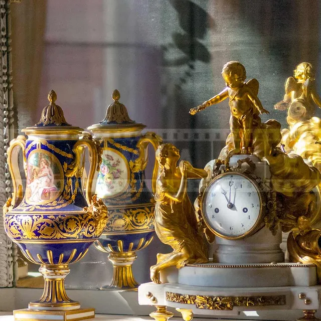 clock in front of a mirror surrounded by two vases